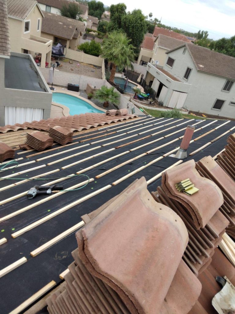 stack of clay roof tiles on top of a roof being installed with the roof battens already in place