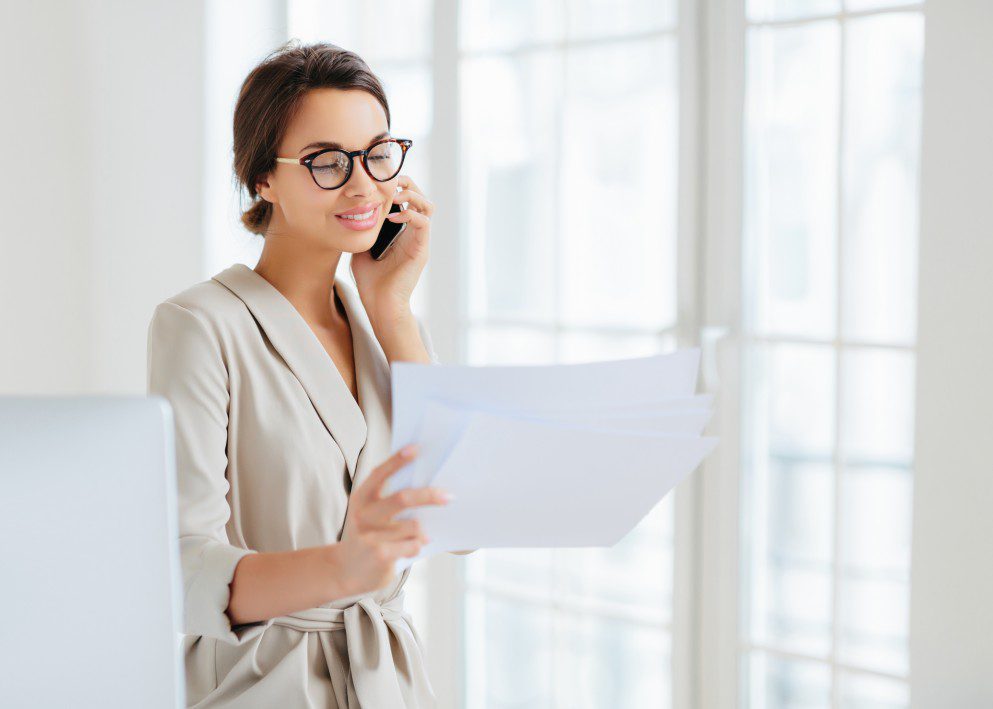 lady in formal clothes holding two documents making a call to Mikku and Sons roofing company