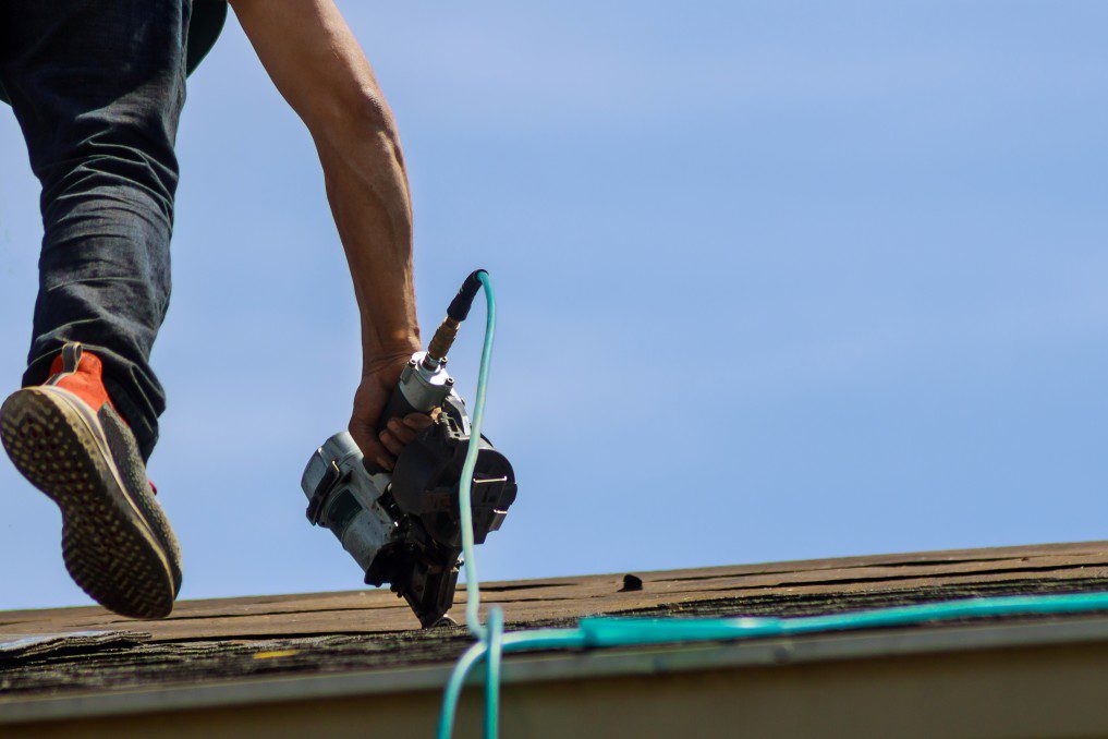 A roofer replacing shingles on a roof