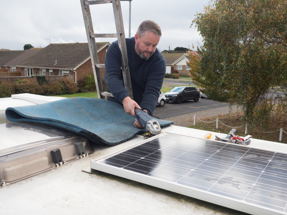 man on top of a ladder replacing old mobile solar panels for new ones